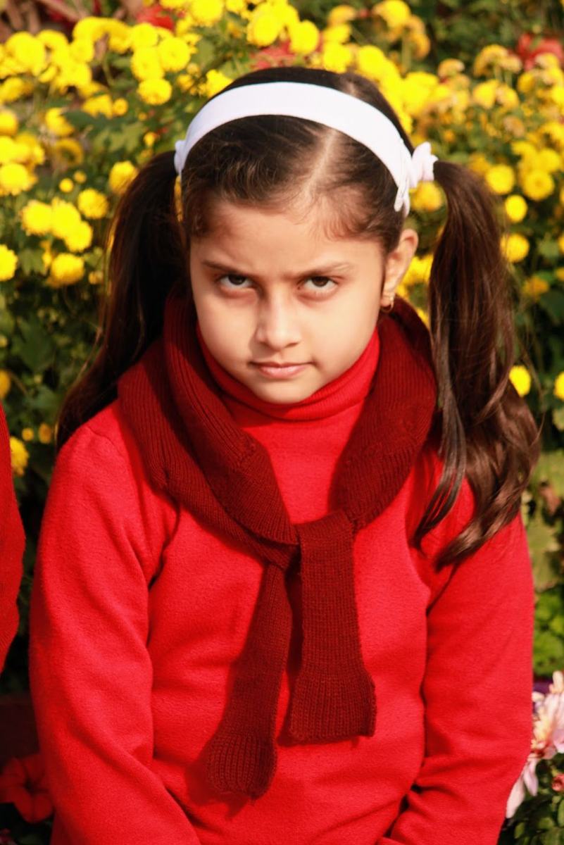 A student in a red winter uniform standing before yellow marigolds