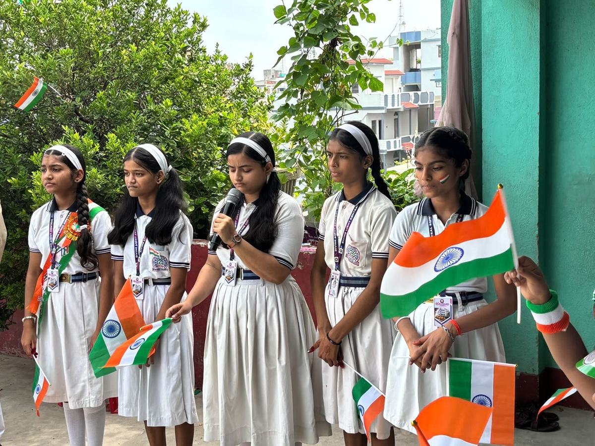 Students in white uniforms with tricolour flags on Independence Day